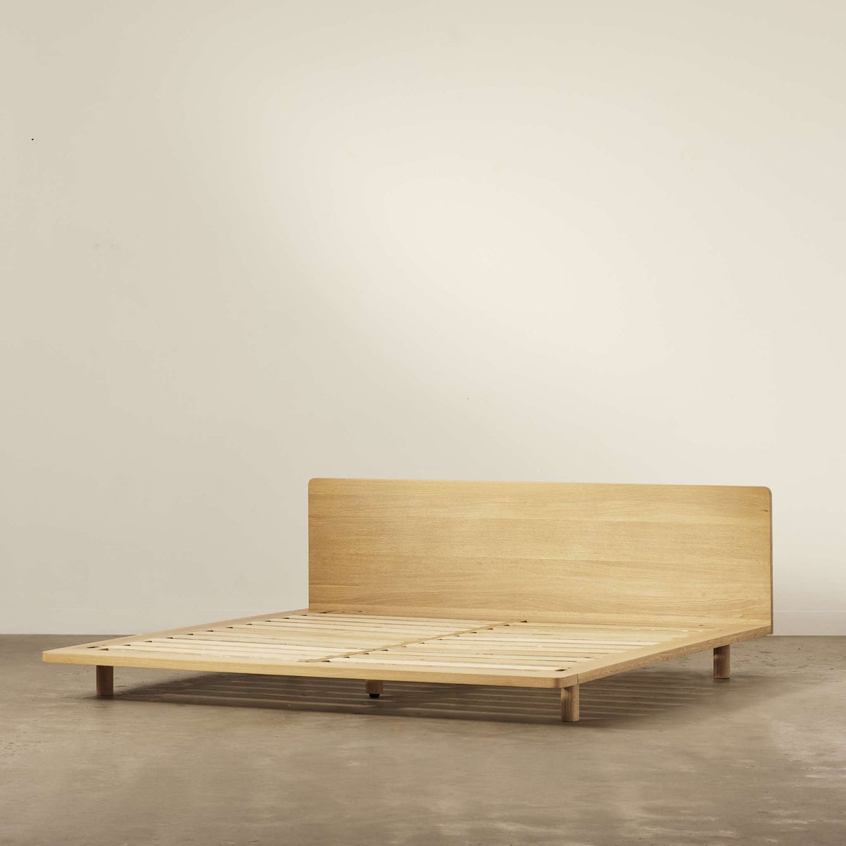 Lagos timber bed frame in natural solid oak, showing its low-profile design and wide headboard - Totem Road