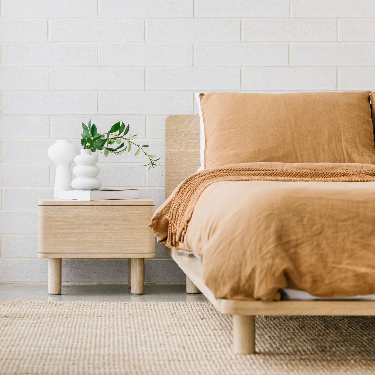 Lagos timber bed frame in solid oak, styled with warm-toned linen bedding and matching bedside table in a minimalist space – Totem Road